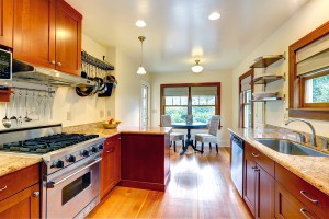 Practical kitchen room interior. View of cabinets steel appliances hanging pot rack. Kitchen room has a small dining area